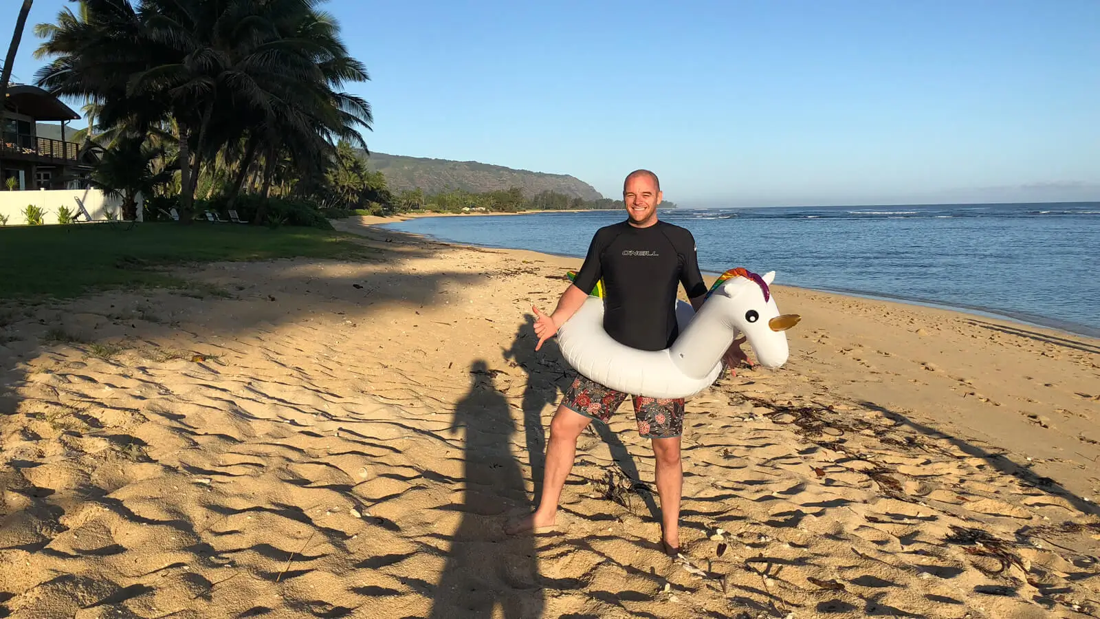 Paul Summers on a beach in Hawaii with an inflatable unicorn